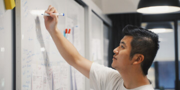 Man in office writing on a whiteboard.