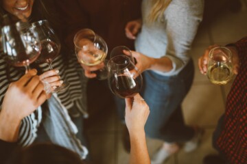 Women clinking wine glasses with red and white wine in them