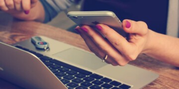 Woman-looking-at-phone-with-laptop