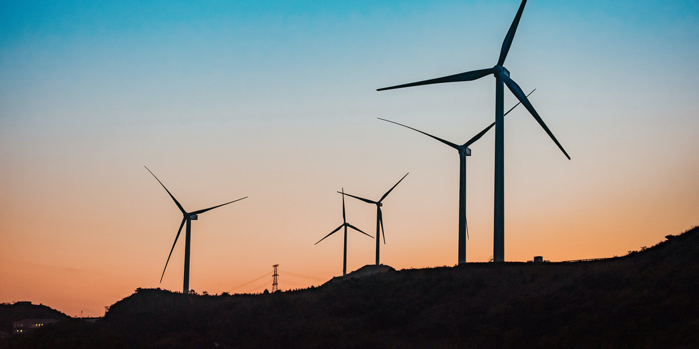 wind turbines in front of a sunset and hills