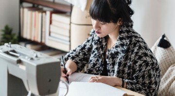 person sitting at a desk with sewing machine and sketching