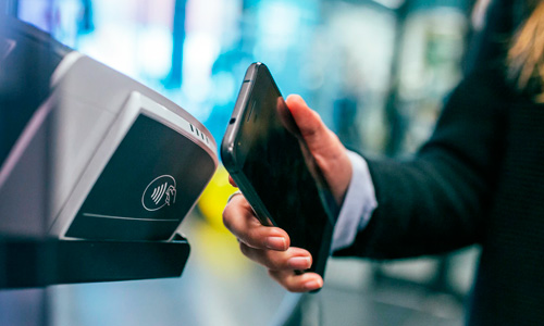 Person using their cell phone to pay by holding it in front of a scanner.