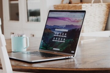 Laptop with Google browser on a table with a blue cup of coffee.