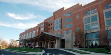 Outside of a large brick medical building under a blue sky.