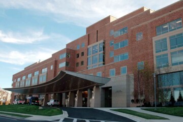 Outside of a large brick medical building under a blue sky.