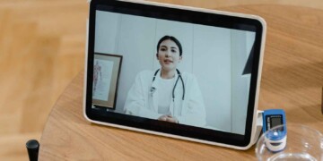A doctor video calling on an iPad sitting on a table.