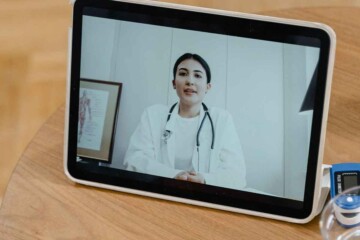 A doctor video calling on an iPad sitting on a table.