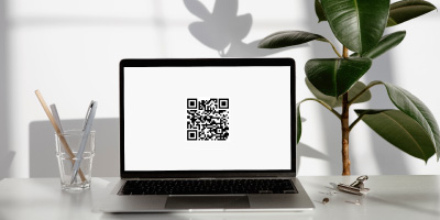 QR code on a white background on a laptop computer screen sitting on a tidy desk.