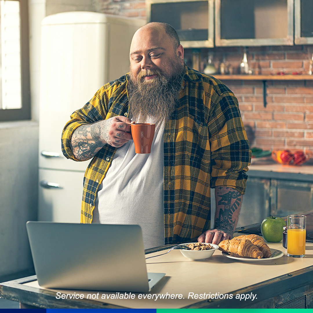 Guy sipping on coffee while looking at laptop.