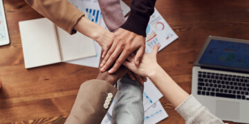 Five hands stacked on top of each other for a huddle.