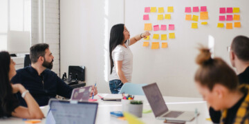 A woman placing a sticky note on the whiteboard.