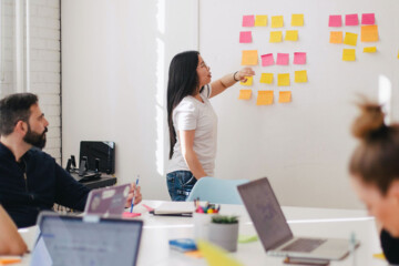 A woman placing a sticky note on the whiteboard.