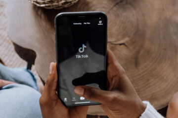 A close up of a person holding a phone with TikTok on the screen.