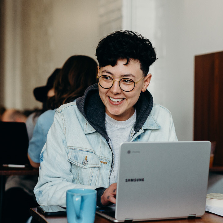 woman working at coffee shop with laptop at a table.