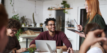 A group of colleagues gathered around a desk while smiling.