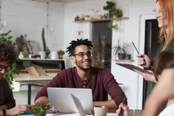 A group of colleagues gathered around a desk while smiling.