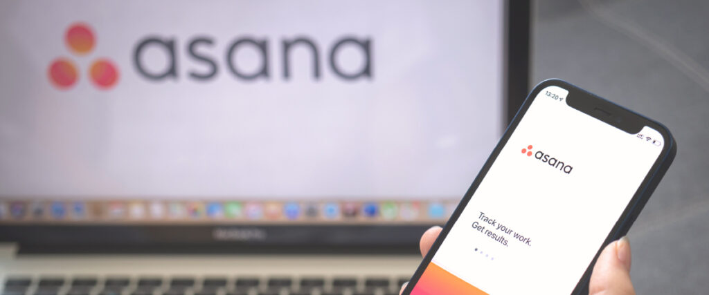 A computer and phone screen each show the Asana project management software logo.