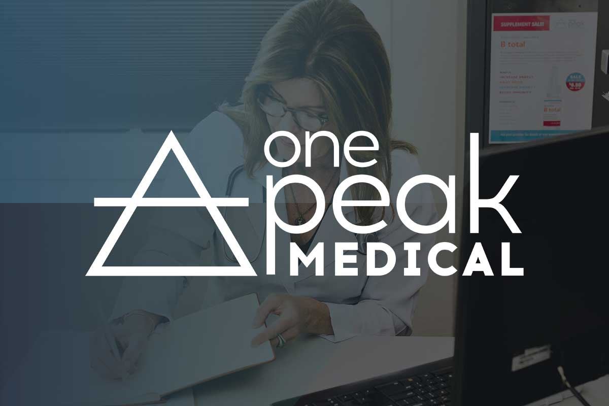 OnePeak Medical founder and owner, Nisha Jackson sits at her desk in front of a computer with their logo overlaid on top.