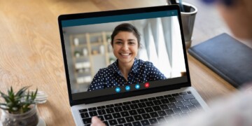 Laptop on desk open during a virtual meeting.