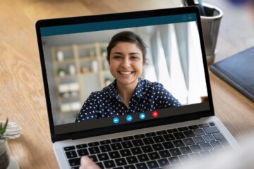 Laptop on desk open during a virtual meeting.