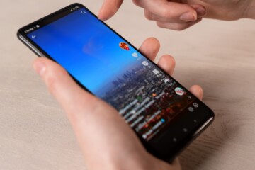 Hands holding a smartphone displaying a cityscape on the screen.