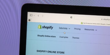 Shopify online store homepage on a laptop screen with navigation menu and Shopify logo.