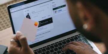 Woman entering payment details on a laptop to purchase a sweatshirt.